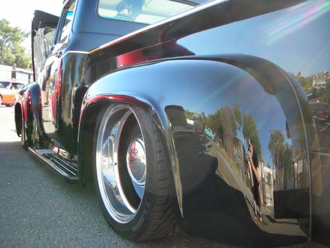 1998 Ford Crown Victoria - The shiny black paint reflects the surroundings, including trees and buildings.