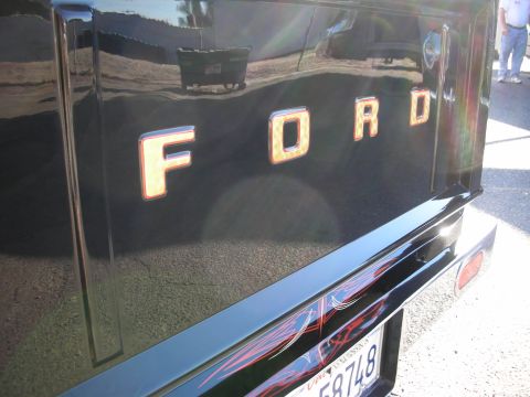 1998 Ford Crown Victoria - The rear of a black Ford truck shows off its tailgate lettering and custom pinstriping on the bumper.