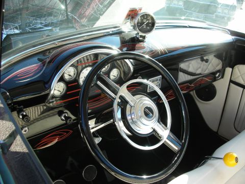 1998 Ford Crown Victoria - The interior of a custom car features a black dashboard with pinstriping, multiple gauges, and a chrome steering wheel.