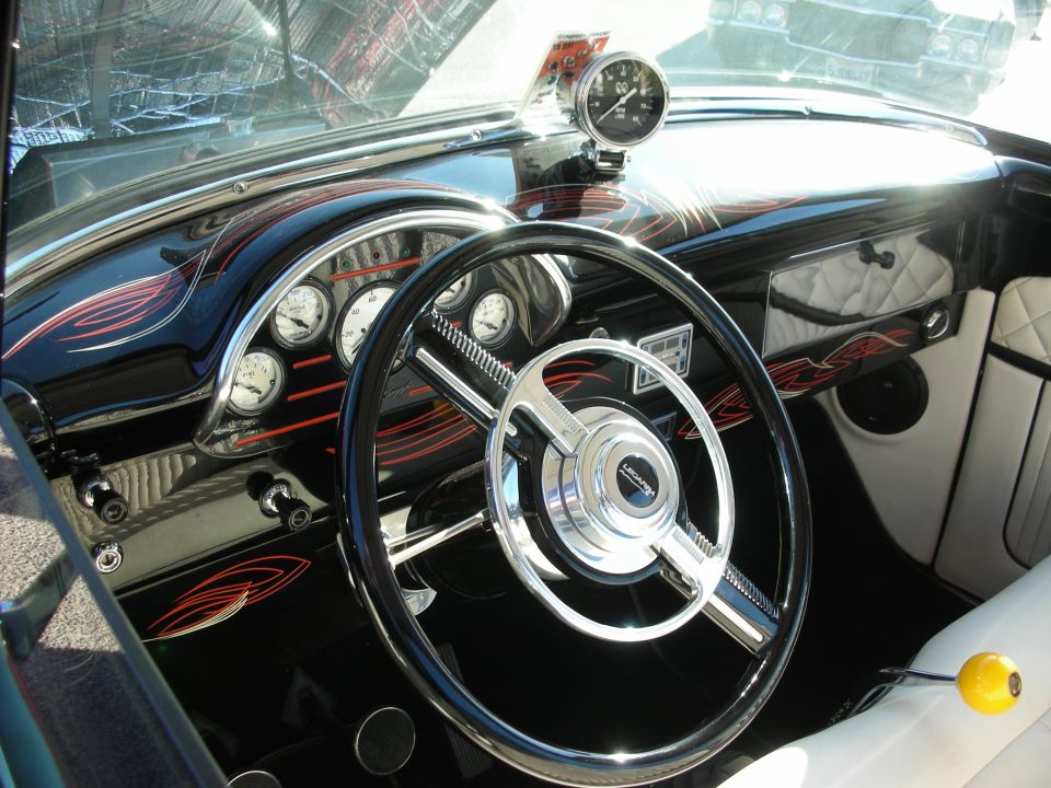 Custom car interior with black dashboard, chrome accents, and a tachometer