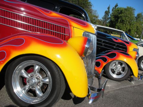 1998 Ford Crown Victoria - Custom hot rods with flame paint jobs displayed at an outdoor event.