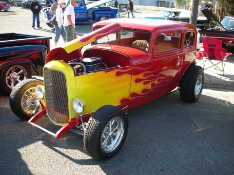 1998 Ford Crown Victoria - A custom hot rod with a vibrant flame paint job is displayed at an outdoor event.