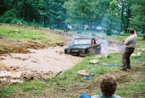 1972 Ford Bronco - A Jeep CJ-5 is stuck in a mud pit with a person watching from the side.