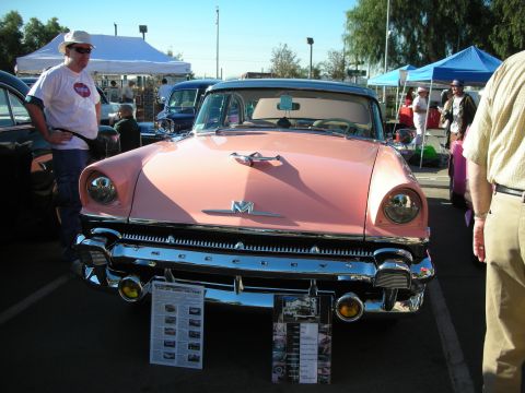 1998 Ford Crown Victoria - A pink 1955 Mercury Monterey is displayed at an outdoor car show with informational posters.
