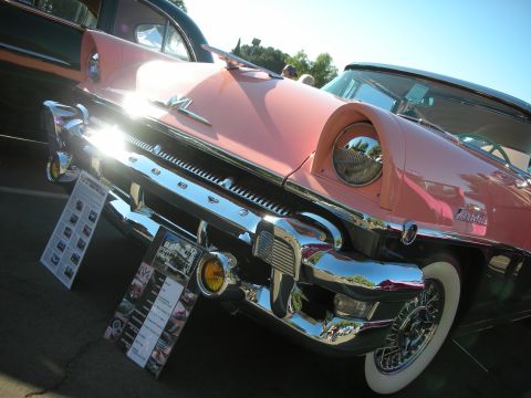 1998 Ford Crown Victoria - A pink classic car is displayed with informational placards on its front bumper.