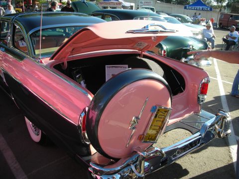 1998 Ford Crown Victoria - A two-tone pink and black 1956 Mercury Montclair is displayed with its trunk open and a continental kit holding the spare tire.