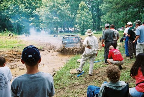 1972 Ford Bronco - A group of people watch an off-road vehicle navigate a muddy track.
