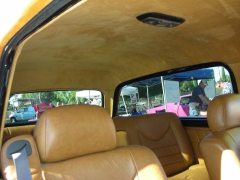 1998 Ford Crown Victoria - Interior view of a car showing tan leather seats and a glimpse of an outdoor event with tents and vehicles.