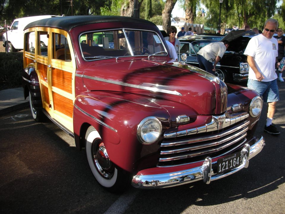 Maroon woodie station wagon with chrome grille and whitewall tires. License plate reads 121 164