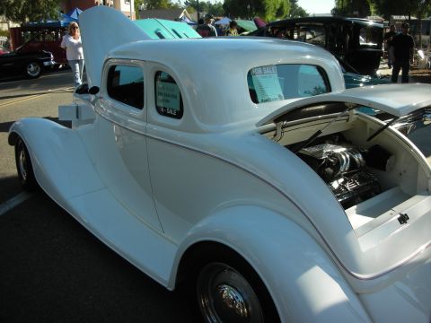 1998 Ford Crown Victoria - A white coupe is displayed with its hood and trunk open, revealing the engine and a 'For Sale' sign in the rear window.
