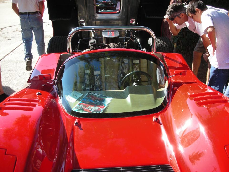 Red sports car with racing seats and a roll cage, viewed from the front