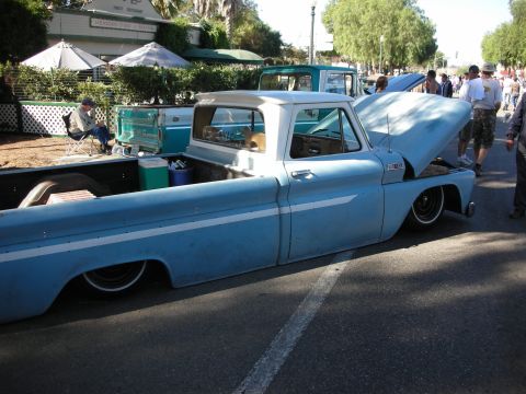 1998 Ford Crown Victoria - A classic pickup truck is displayed with its hood open, parked on a street during an event.