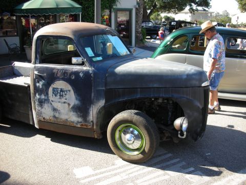 1998 Ford Crown Victoria - A weathered pickup truck sits next to a green sedan at an outdoor event.