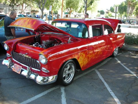 1998 Ford Crown Victoria - A classic red Chevrolet sedan with flame decals is displayed with its hood and trunk open.