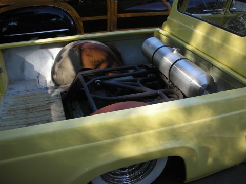 1998 Ford Crown Victoria - Customized yellow pickup truck bed features a large fuel tank and roll cage, with wood paneling visible in the background.