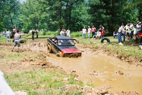 1972 Ford Bronco - A 1972 Ford Bronco navigates a muddy obstacle course with spectators watching from the sidelines.