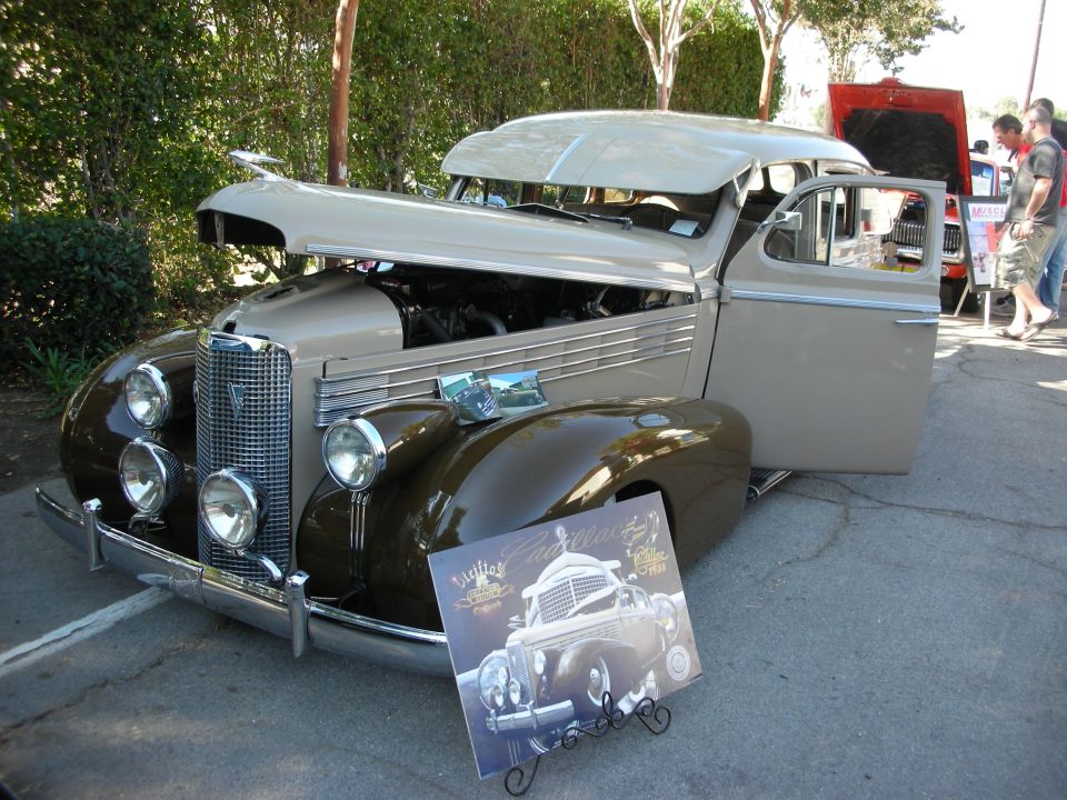 Tan and brown vintage Cadillac with hood open and door ajar, display card in front