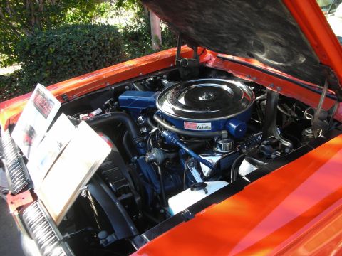 1998 Ford Crown Victoria - The engine bay of an orange classic car is displayed with the hood open, a prominent chrome air cleaner and informational pamphlets.