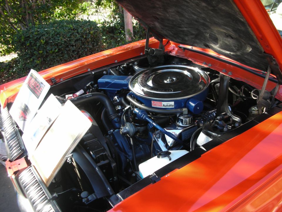 Engine bay of an orange car with a chrome air cleaner and Autolite branding