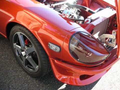 1998 Ford Crown Victoria - Close-up view of the front fender and exposed engine of a bright orange sports car.