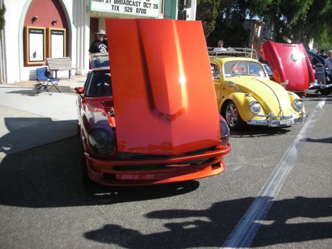 1998 Ford Crown Victoria - Two cars with hoods open at an outdoor event, with a building in the background.