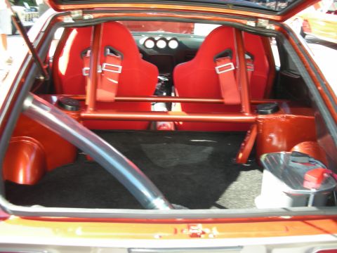 1998 Ford Crown Victoria - The interior of a car shows red racing seats and a prominent roll cage, with a large exhaust pipe visible.
