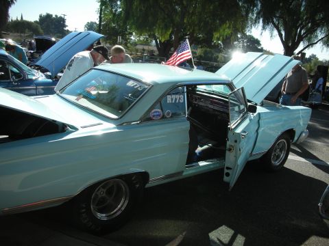 1998 Ford Crown Victoria - A light blue classic coupe is displayed with its hood and door open, an American flag on the roof.