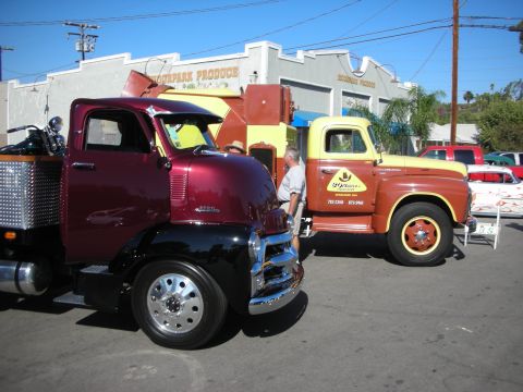 1998 Ford Crown Victoria - Two vintage trucks are parked outside a building that reads "Moorpark Produce" on a sunny day.