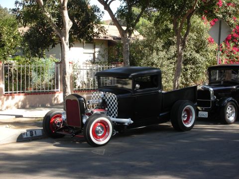 1998 Ford Crown Victoria - Two black hot rod trucks parked on a residential street.