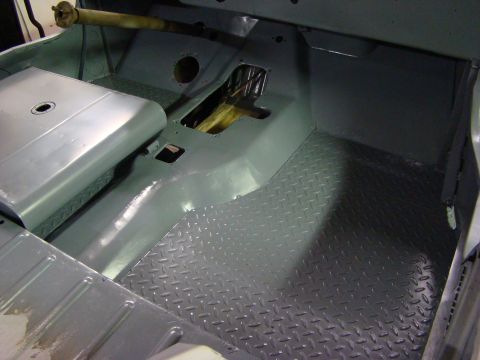 1948 Jeep Wrangler - The interior floor of a vehicle shows gray diamond plate and painted metal surfaces, with visible wiring near the transmission tunnel.