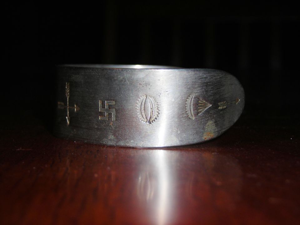 Silver ring with swastika, arrows, and other etched symbols