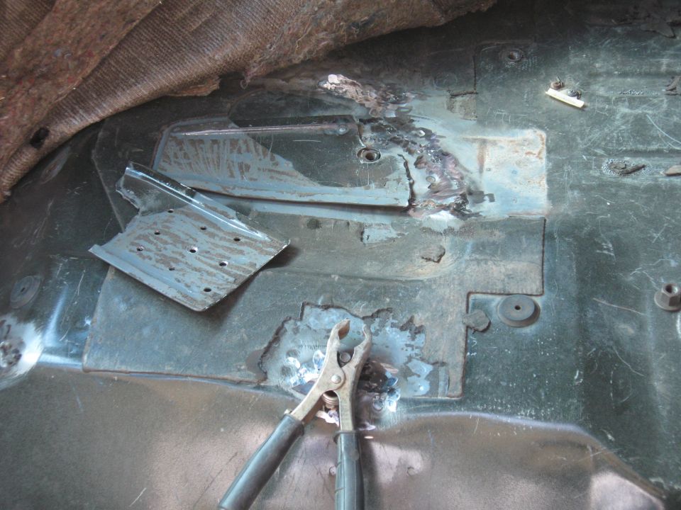 vehicle floor pan with welding repairs and a pair of pliers