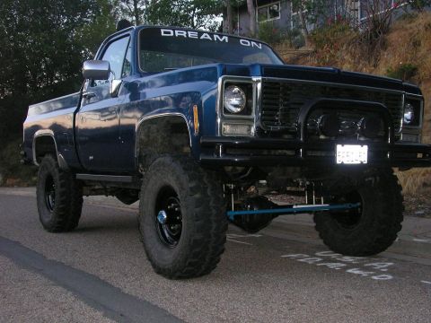 1979 Chevrolet C/K Pickup - A lifted blue pickup truck with "DREAM ON" visible on the windshield.