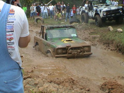 1972 Ford Bronco - A green 1972 Ford Bronco navigates a muddy off-road course, its front end submerged in the mire.