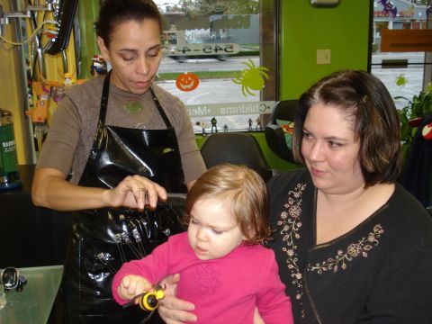 2000 Ford Crown Victoria - A hairdresser cuts a young child's hair in a salon, with a woman looking on.