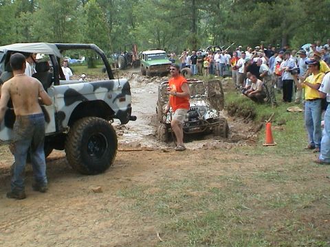 1972 Ford Bronco - A camouflaged 1972 Ford Bronco navigates a muddy off-road course with spectators watching.