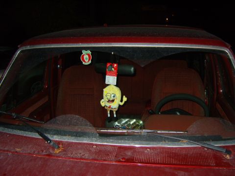 1989 Ford Bronco - The interior of a red vehicle, a Spongebob plush and an apple air freshener.