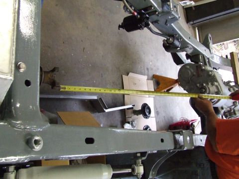 1967 Ford Bronco - Measuring the vehicle frame with a tape measure, showing a transfer case and suspension components.