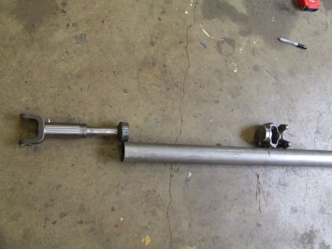 1967 Ford Bronco - Two driveshaft components are laid out on a concrete floor, possibly for repair or replacement.