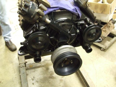 1967 Ford Bronco - A black engine assembly is shown on an engine stand, with various pulleys and components visible.