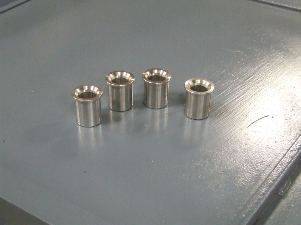 four metal bushings on a gray surface