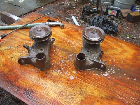 1967 Ford Bronco - Two car water pumps are shown on a wet wooden surface, possibly being cleaned or prepared for installation.