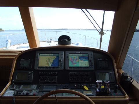 1976 Ford F-150 - The helm of a boat shows multiple navigation screens displaying charts and data, with the open water visible through the windows.