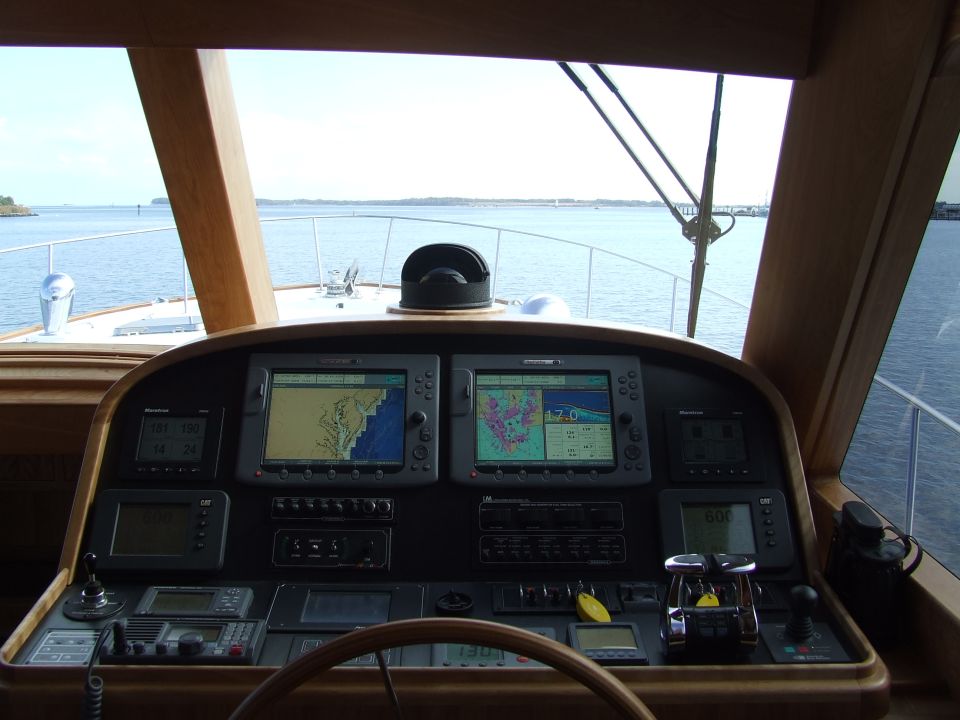 Boat helm with two navigation screens showing maps, compass, and speed