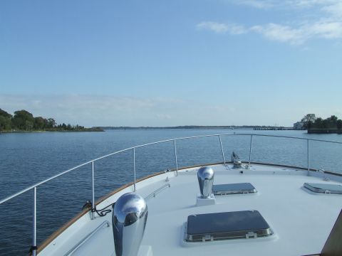 1976 Ford F-150 - View from the bow of a boat sailing on a tranquil bay, with trees and houses visible on the distant shore.