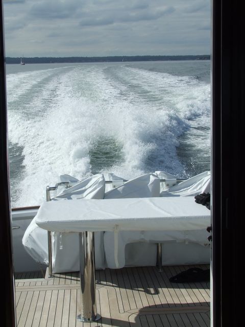 1976 Ford F-150 - The wake of a boat is visible as it travels across the water, with covered seating and a table on the deck.