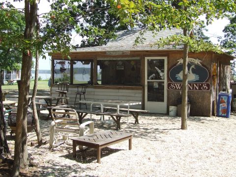 1976 Ford F-150 - A rustic building with outdoor seating and a sign for "SWNN'S" sits by the water.