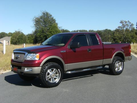 2005 Ford F-150 - A dark red/maroon Ford F-150 extended-cab pickup with two-tone tan lower body cladding, shown in 3/4 front view. It has a lift, aftermarket…