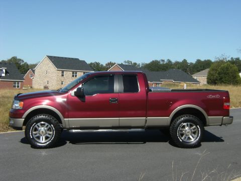2005 Ford F-150 - A maroon/burgundy Ford F-150 extended-cab pickup with two-tone tan lower body cladding, shown in profile on a paved lot. It has aftermarket…