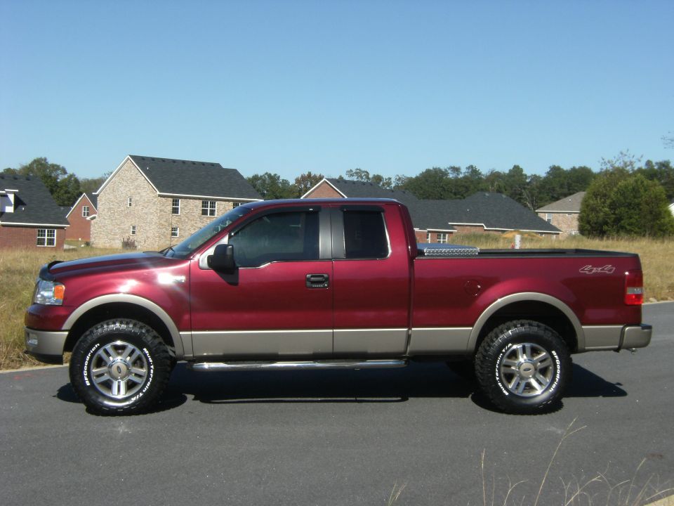 Maroon Ford F-150 extended-cab pickup, side view, with tan lower cladding and off-road tires
